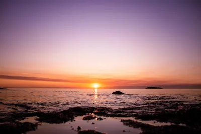 A tranquil sunset over Coles Bay, with hues of orange and pink reflecting on the water.