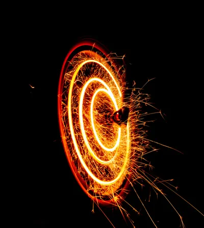 A dramatic image of a Ferris wheel illuminated by fiery effects.